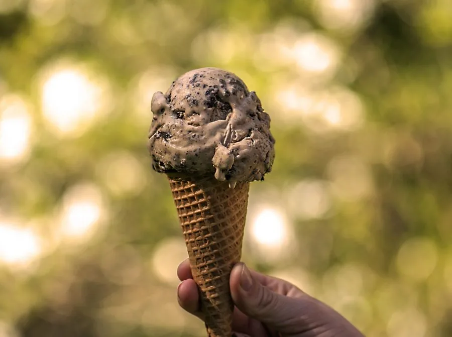 Coffee crunch ice cream cone held outdoors